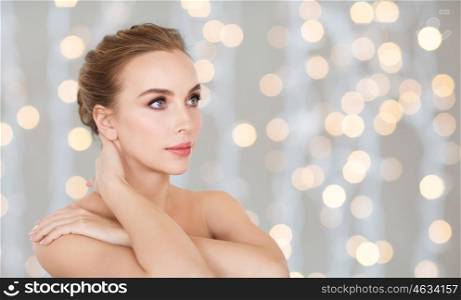 beauty, people and bodycare concept -beautiful young woman face and hands over holidays lights background
