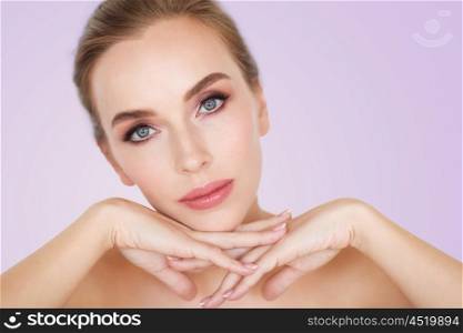 beauty, people and bodycare concept -beautiful young woman face and hands over violet background