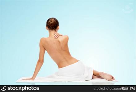 beauty, people and bodycare concept - beautiful young woman in white towel with bare top over blue background. beautiful young woman in white towel with bare top