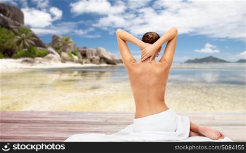 beauty, people and bodycare concept - beautiful young woman in white towel with bare top over exotic beach background. beautiful woman in towel with bare top on beach. beautiful woman in towel with bare top on beach