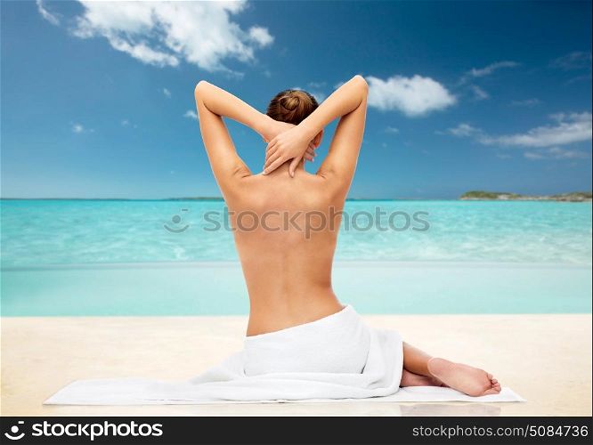 beauty, people and bodycare concept - beautiful young woman in white towel with bare top tropical beach background. beautiful young woman in white towel with bare top. beautiful young woman in white towel with bare top