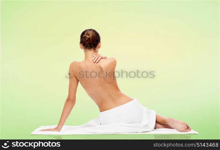 beauty, people and bodycare concept - beautiful young woman in white towel with bare top over green natural background. beautiful young woman in white towel with bare top