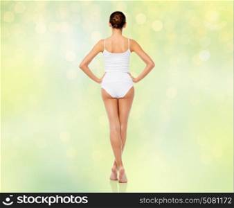 beauty, people and bodycare concept - beautiful young woman in white underwear from back over summer green lights background. beautiful woman in white underwear over green