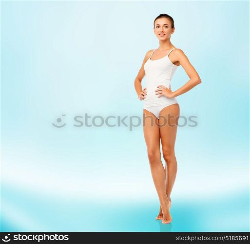 beauty, people and bodycare concept - beautiful young woman in white underwear over blue background. beautiful young woman in white underwear