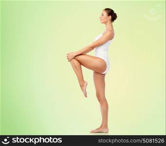 beauty, people and bodycare concept - beautiful young woman in white underwear over green background. beautiful young woman in white underwear