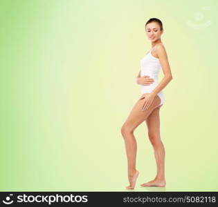beauty, people and bodycare concept - beautiful young woman in white underwear over green background. beautiful young woman in white underwear