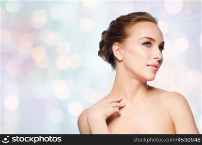 beauty, people and bodycare concept - beautiful young woman touching her neck over blue holidays lights background
