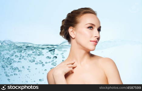 beauty, people and bodycare concept - beautiful young woman touching her neck over blue background with water splash