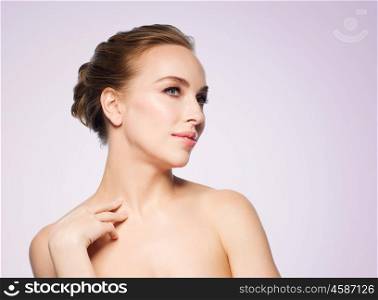 beauty, people and bodycare concept - beautiful young woman touching her neck over violet background