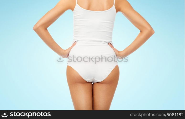 beauty, people and bodycare concept - close up of beautiful young woman body in white underwear from back over blue background. close up of woman body in white underwear