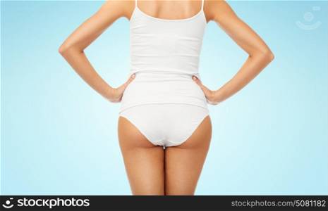 beauty, people and bodycare concept - close up of beautiful young woman body in white underwear from back over blue background. close up of woman body in white underwear