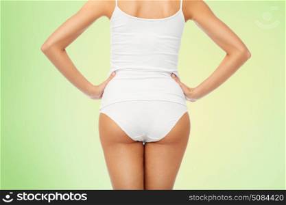 beauty, people and bodycare concept - close up of beautiful young woman body in white underwear from back over green natural background. close up of woman body in white underwear. close up of woman body in white underwear