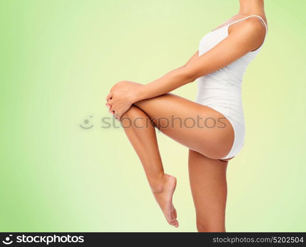 beauty, people and bodycare concept - close up of beautiful young woman in white underwear over green background. close up of young woman body in white underwear