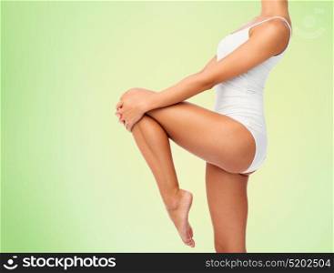 beauty, people and bodycare concept - close up of beautiful young woman in white underwear over green background. close up of young woman body in white underwear