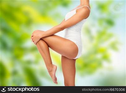 beauty, people and bodycare concept - close up of beautiful young woman in white underwear over green natural background. close up of young woman body in white underwear. close up of young woman body in white underwear