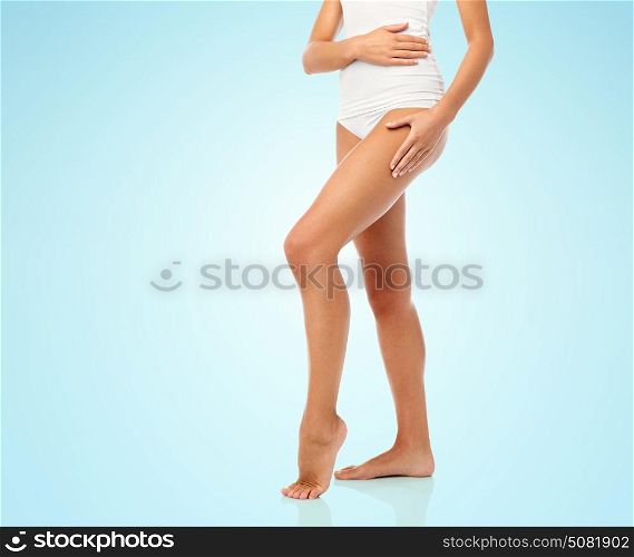 beauty, people and bodycare concept - legs of beautiful young woman in white underwear over blue background. legs of beautiful young woman in white underwear
