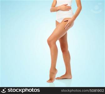 beauty, people and bodycare concept - legs of beautiful young woman in white underwear over blue background. legs of beautiful young woman in white underwear