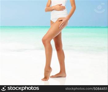 beauty, people and bodycare concept - legs of beautiful young woman in white underwear over beach background. legs of woman in white underwear on beach. legs of woman in white underwear on beach