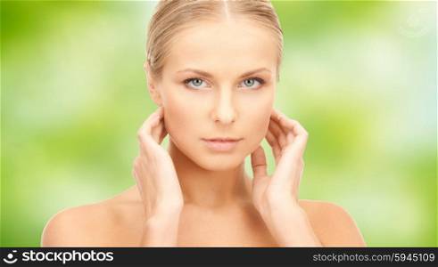 beauty, people and health care concept - beautiful young woman touching her neck over green natural background