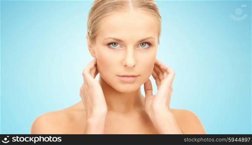 beauty, people and health care concept - beautiful young woman touching her neck over blue background