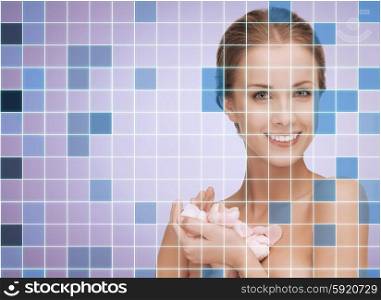 beauty, people and health concept - beautiful smiling young woman with flower petals and bare shoulders over violet background with squared grid