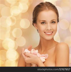 beauty, people and health concept - beautiful smiling young woman with flowers and bare shoulders over beige lights background