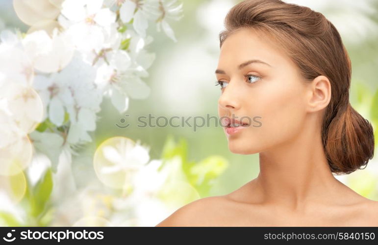 beauty, people and health concept - beautiful young woman face looking aside over green blooming garden background