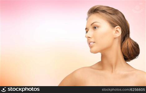 beauty, people and health concept - beautiful young woman face looking aside over pink background