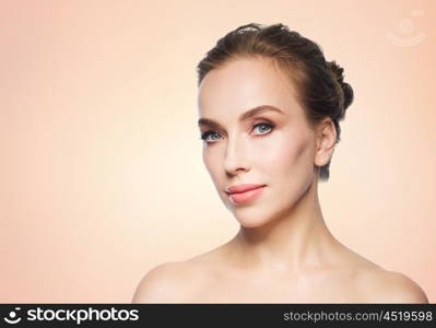 beauty, people and health concept - beautiful young woman face over beige background