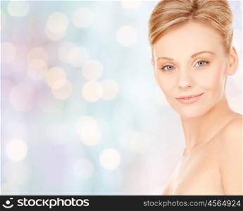 beauty, people and health concept - beautiful young woman face over blue holidays lights background