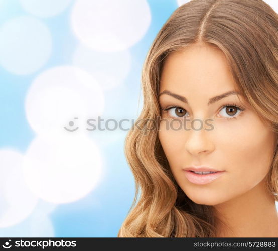 beauty, people and health concept - beautiful young woman face over blue lights background