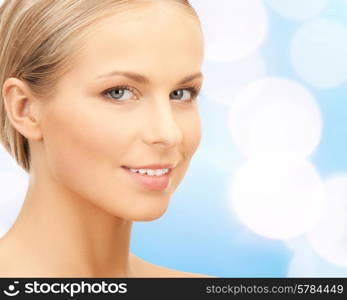 beauty, people and health concept - beautiful young woman face over blue lights background