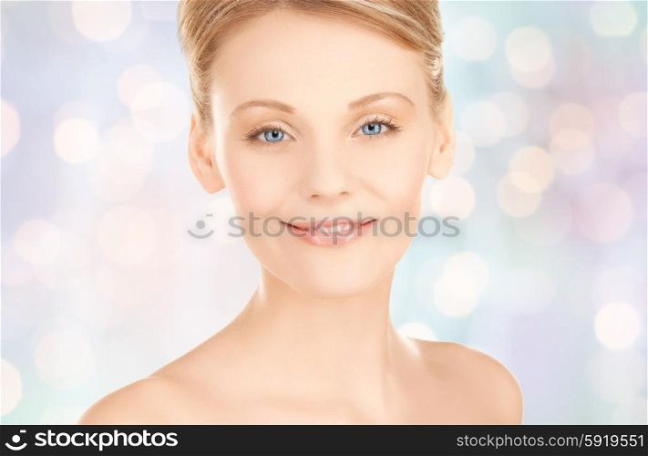 beauty, people and health concept - beautiful young woman face over blue lights background