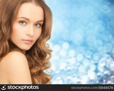 beauty, people and health concept - beautiful young woman face over blue lights background