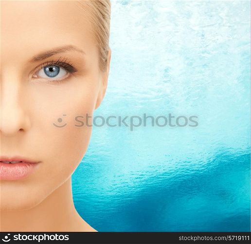 beauty, people and health concept - beautiful young woman face over blue ripple water background