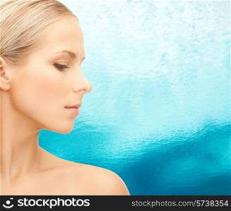 beauty, people and health concept - beautiful young woman face over blue ripple water background