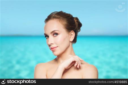 beauty, people and health concept - beautiful young woman face over blue sea and sky background