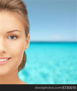 beauty, people and health concept - beautiful young woman face over blue water and sky background