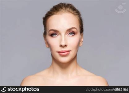 beauty, people and health concept - beautiful young woman face over gray background