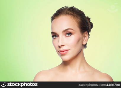 beauty, people and health concept - beautiful young woman face over green background