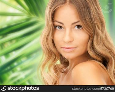 beauty, people and health concept - beautiful young woman face over green palm leaves background