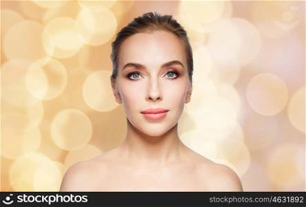 beauty, people and health concept - beautiful young woman face over holidays lights background