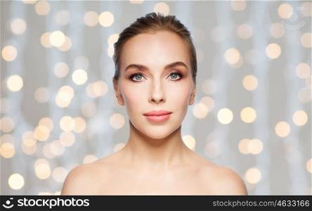 beauty, people and health concept - beautiful young woman face over holidays lights background
