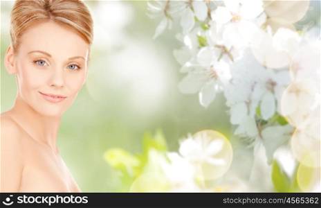 beauty, people and health concept - beautiful young woman face over natural spring cherry blossom background
