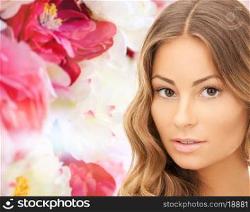 beauty, people and health concept - beautiful young woman face over pink floral background