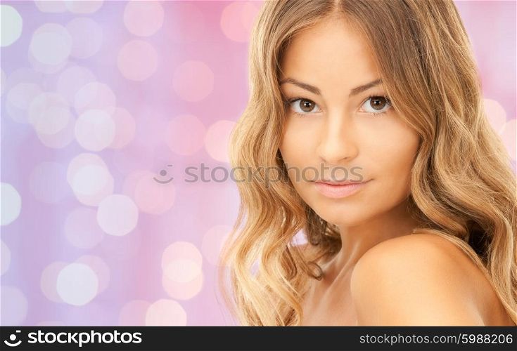 beauty, people and health concept - beautiful young woman face over pink lights background