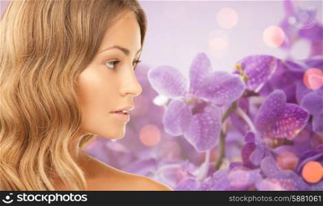 beauty, people and health concept - beautiful young woman face over purple orchid flowers background