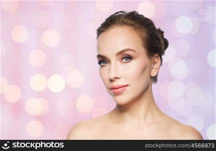 beauty, people and health concept - beautiful young woman face over rose quartz and serenity lights background