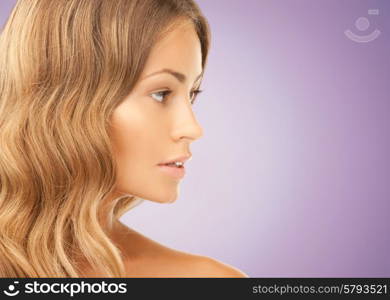 beauty, people and health concept - beautiful young woman face over violet background