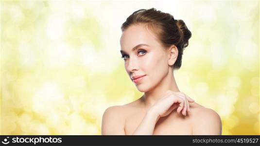 beauty, people and health concept - beautiful young woman face over yellow holidays lights background